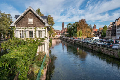 Buildings by canal against sky in city