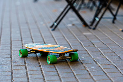 Skateboard with green wheels on a paved sidewalk, close-up