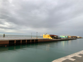 Pier over sea by buildings against sky