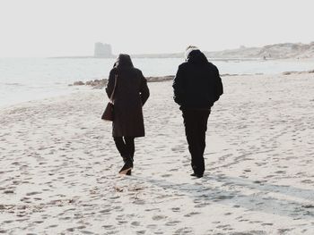 Rear view of people walking on beach