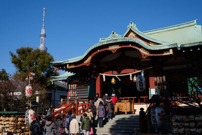 Group of people in traditional building against sky in city