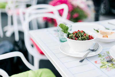 On the table in an arab restaurant there is a parsley tabbouleh salad with pomegranate seeds. 