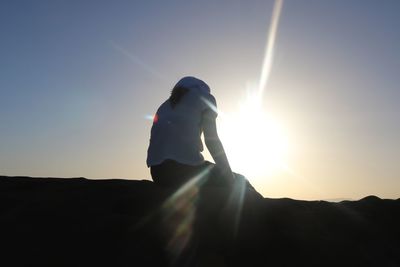 Silhouette person standing on mountain against sky during sunset