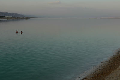 People swimming in sea against sky