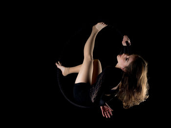 Portrait of young woman against black background