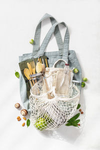 Directly above shot of bag with various objects over white background
