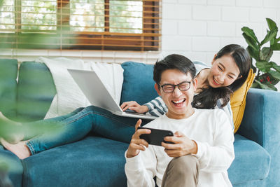 Young woman using mobile phone while sitting on sofa