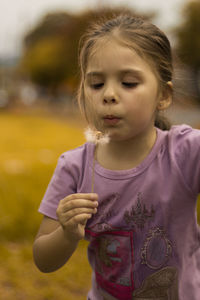 Girl blowing dandelion on field