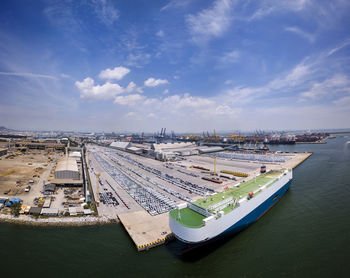 Aerial logistics commercial vehicles waiting to be load on to a car carrier ship at dockyard