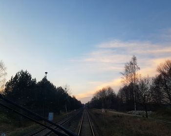 Train on railroad tracks against sky during sunset