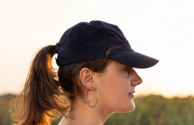 Side view of young woman looking away against clear sky