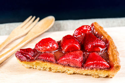 High angle view of strawberry tart slice on cutting board
