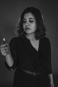 Young woman smoking against wall