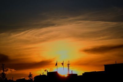Low angle view of silhouette buildings against orange sky