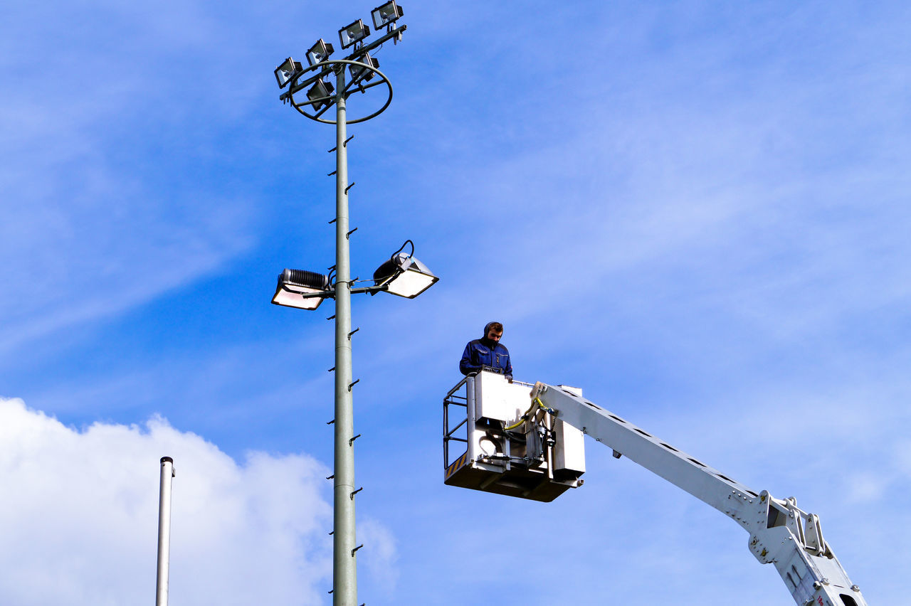 LOW ANGLE VIEW OF WORKER WORKING AGAINST BLUE SKY