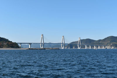 View of suspension bridge over sea against clear sky