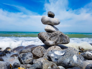 Stack of stones on beach against sky
