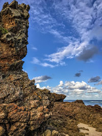 Rock formation by sea against sky