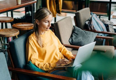 A woman sitting in a coworking space works on a laptop.