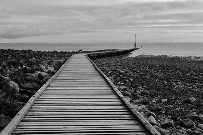 Surface level of empty road by sea against sky