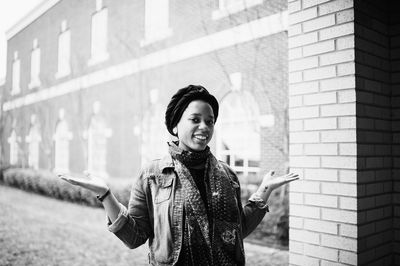 Portrait of smiling young woman standing against building in city