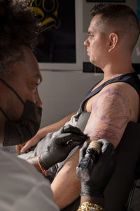 Side view of young man sitting on bed at home