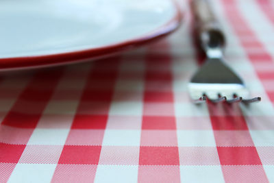 Close-up of plate and fork with tablecloth on table