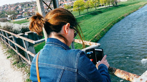 Woman photographing river with mobile phone