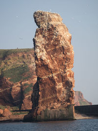 Rock formation by sea against clear sky