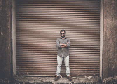 Man standing against shutter of abandoned building