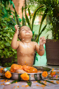 Cute toddler baby boy bathing in decorated bathtub at outdoor from unique perspective