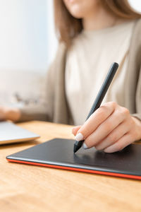 Unrecognizable woman drawing or retouching photos on graphic tablet. home office concept. 