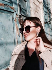 Young woman wearing sunglasses against wall