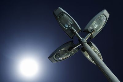 Low angle view of street light against sun in sky