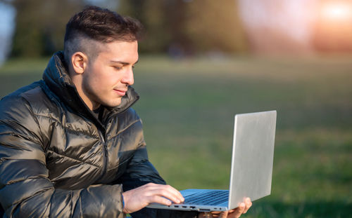 Young man using laptop at park