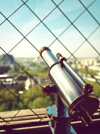 Coin-operated binoculars against fence in city