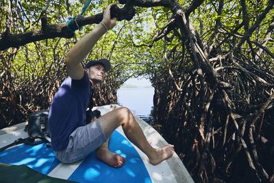 Man sitting on boat in lake against trees
