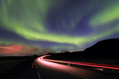 Light trails on road against sky at night