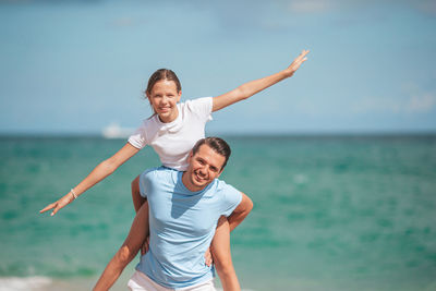 Young woman playing with arms raised standing at beach