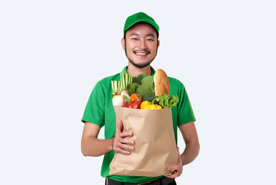 Full length portrait of happy young woman holding apple against white background