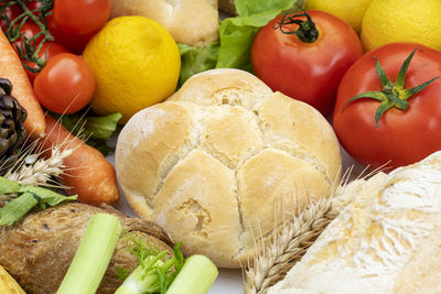 Close up of a rosette bread with various types of vegetables on a white wooden table