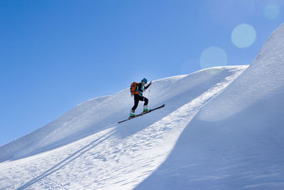Man skiing on snowcapped mountain against sky