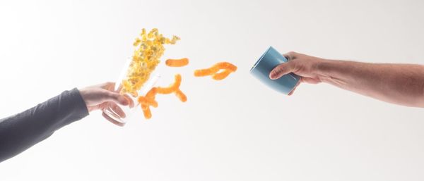 Close-up of hand holding ice cream over white background