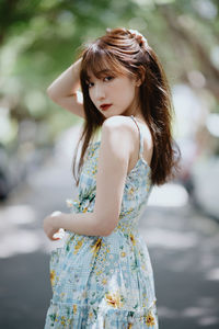 Portrait of young woman standing at park