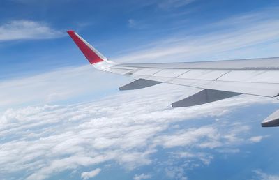 Airplane flying over clouds against blue sky