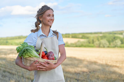 Happy woman holding ice cream in basket on field