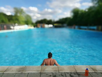 Rear view of man sitting at swimming pool