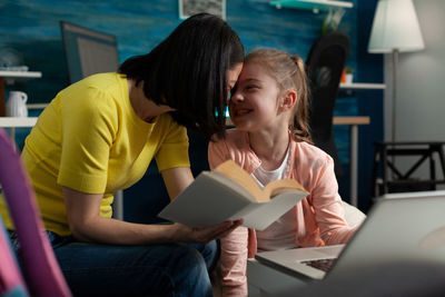 Mother and daughter sitting on book