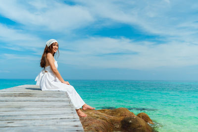 Woman standing by sea against sky