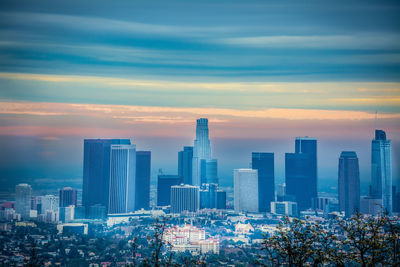 Modern buildings in city against sky during sunset